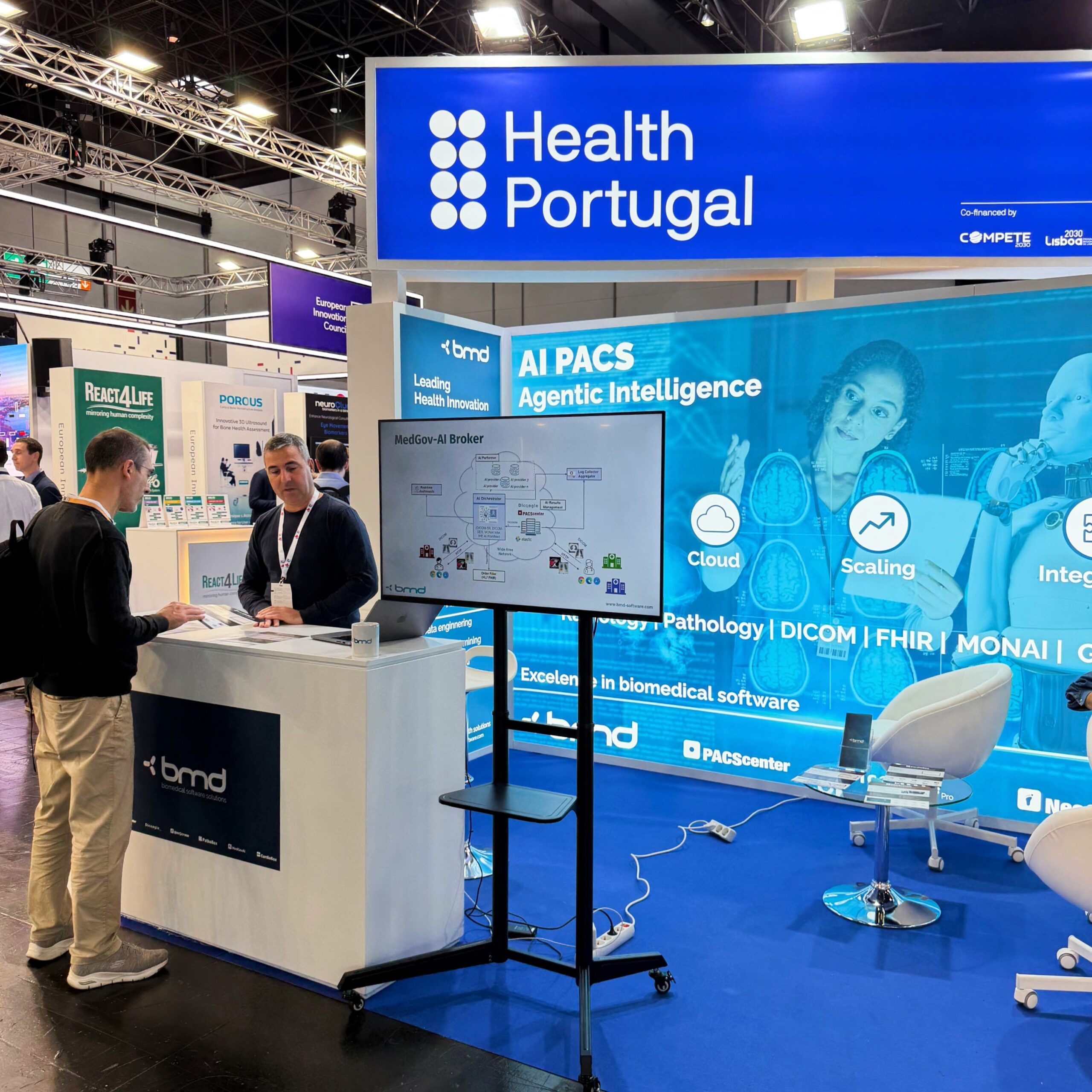 BMD Software team member demonstrating MedGov-AI Broker system on display screen at MEDICA 2025 Health Portugal booth
